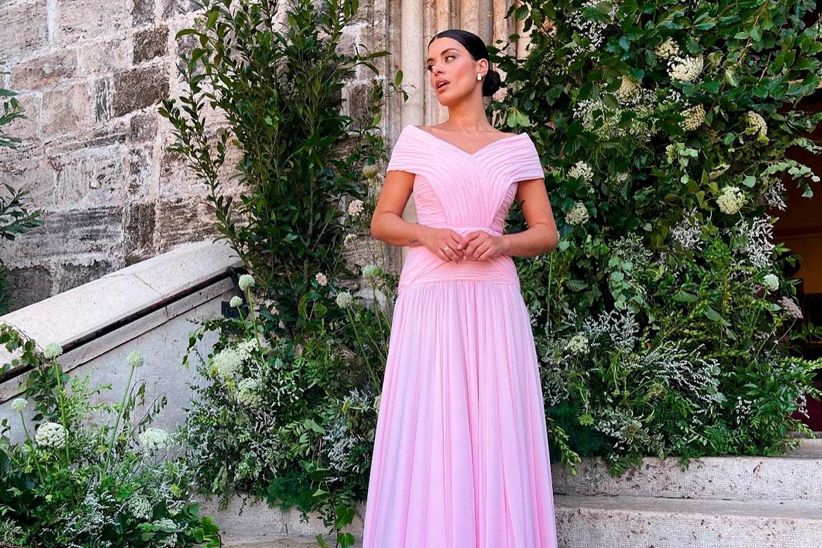 Dulceida con vestido rosa romántico y moño de bailarina delante de una escalera decorada con flores