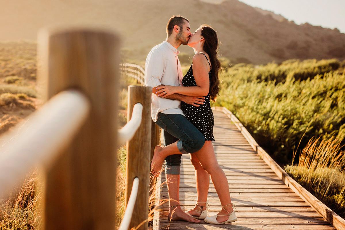 Casal abraçando e beijando em uma passarela de madeira ao ar livre