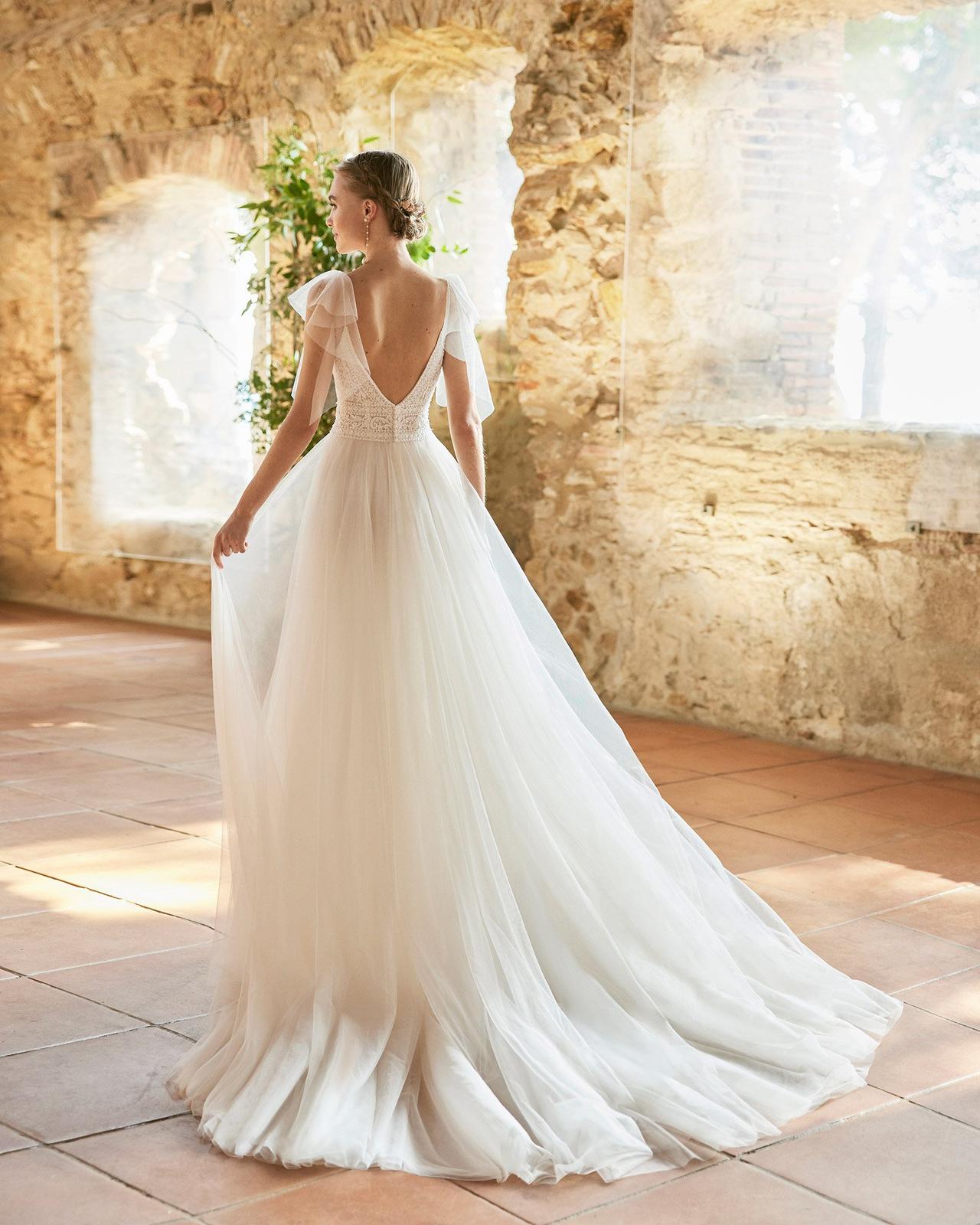 vestido de novia con espalda descubierta y tirantes decorados con lazos de tul