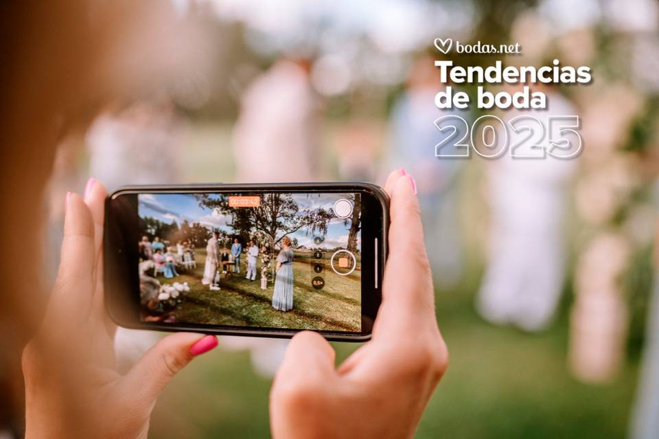 Wedding content creator: mano femenina grabando un momento de una ceremonia civil al aire libre con un teléfono móvil