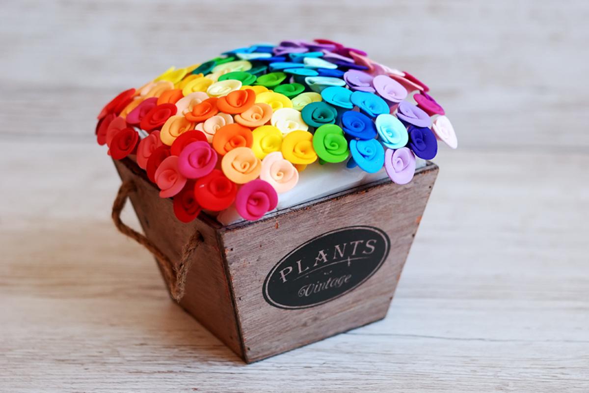 Bonita caja de madera con alfileres con forma de flores de muchos colores clavados en una base en su interior