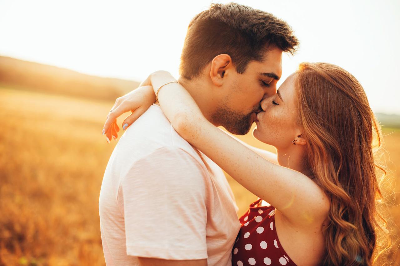 Cosas que los hombres quieren de su relación: tranquilidad. Pareja de chico y chica abrazados besándose en medio de un campo