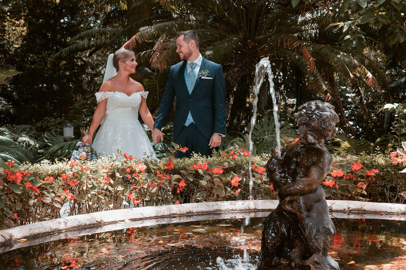 Pareja feliz y cogida de la mano el día de la boda junto a un estanque