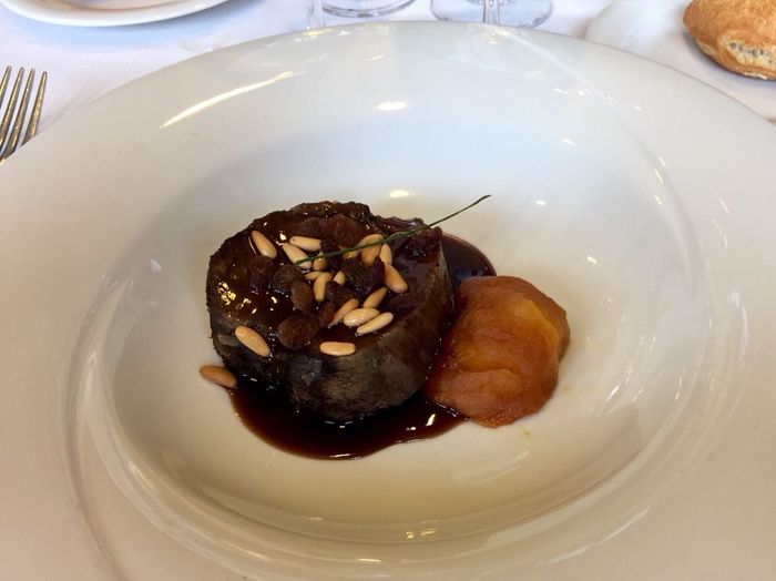 Llata de ternera cocida a baja temperatura con salsa de oporto, piñones, pasas y manzana glaseada
