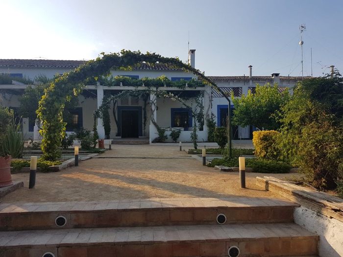 Vista de la puerta principal de lo que es el edificio de la masia desde el jardín