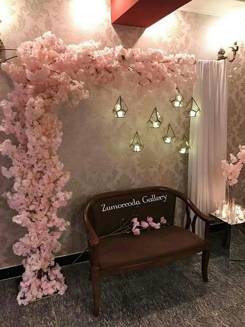 Fotocol con ramas unidas a una cortina, las flores de papel o falsas pegadas y velas con envoltorio 