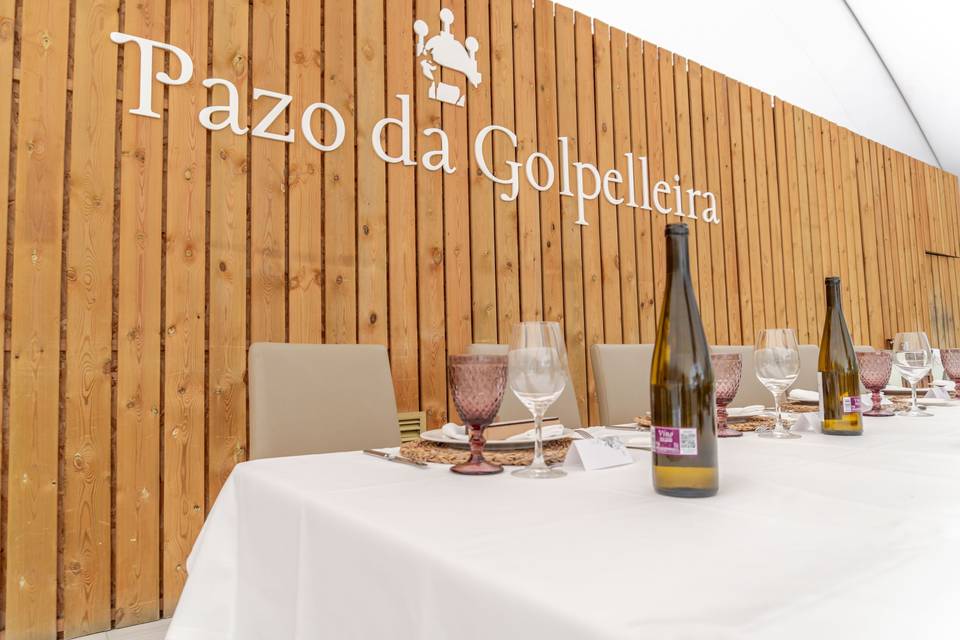 mesa_blanca_botellas_cristal_pared_madera