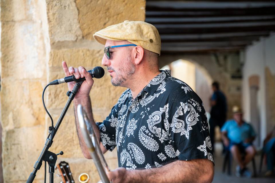 Trombonista cantando al micrófono con pasión